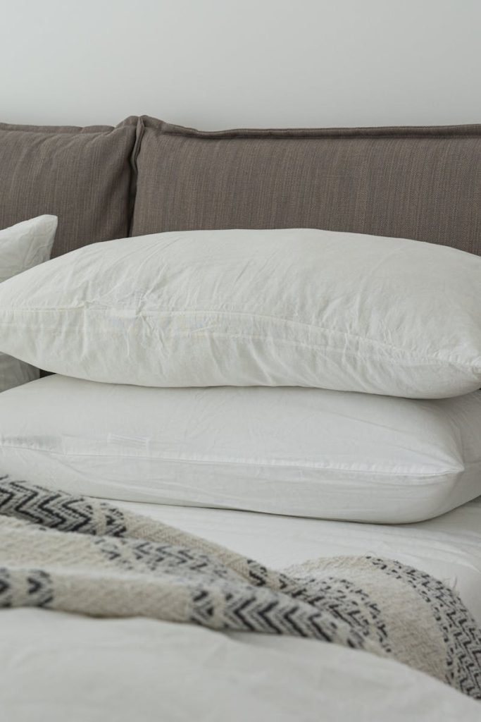 Modern bedroom featuring clean white bedding and pillows for a cozy and inviting atmosphere.