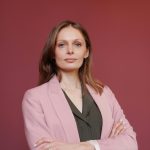 Elegant businesswoman with arms crossed in studio portrait, showcasing leadership and confidence.
